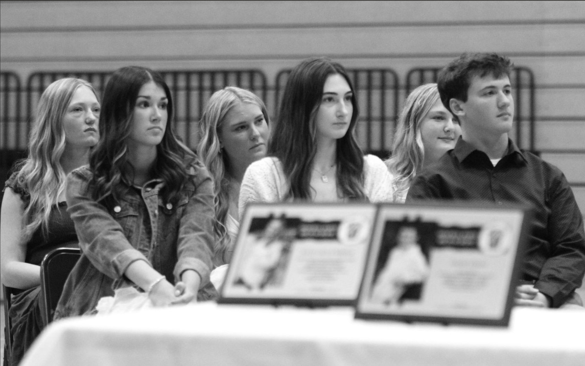 NHS 2nd Year members Madison Nodolf, Addison Burris, Macy Kinch, Alyssa Jones, Kalea Biddick, and Grady Finley listen to the message from Alumni Guest Speaker, Clare (Mitchell) Galvao, during the ceremony.