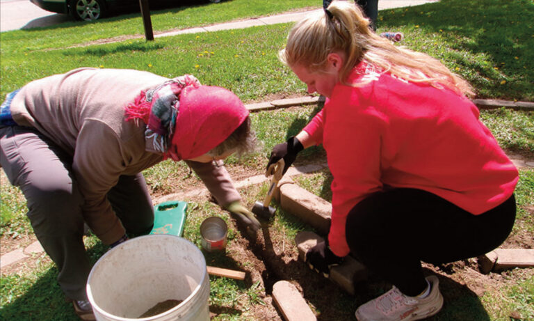 Dorothy Prouty, who suggested a labyrinth at Trinity Episcopal Church more than a decade ago, works with Stephanie Wallace, Mineral Point High School junior, to raise the stones during Key Club Community Service Day.